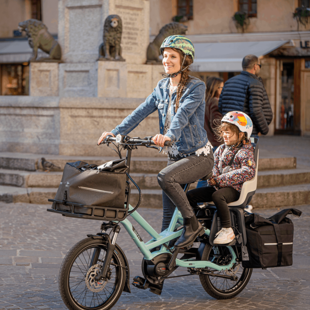 A woman on a Tern ebike carrying her kid and other cargo along with her with ease